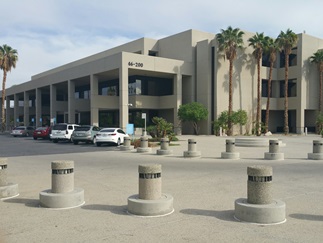 Larson Justice Center framed by manicured trees beneath a clear blue sky