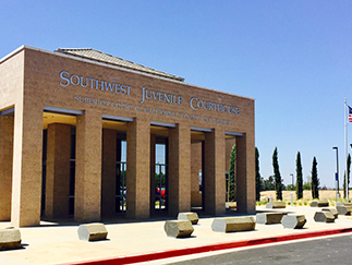 Southwest Juvenile Courthouse framed by manicured trees beneath a clear blue sky.